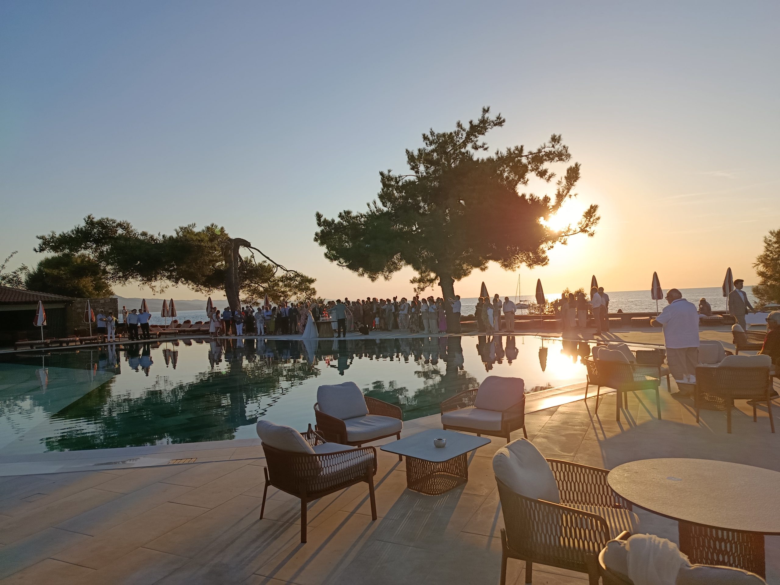 Poolside cake-cutting at Delfinia Hotel in Greece at a waterfront wedding.